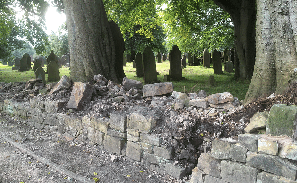 Gritstone dry stone wall with mortared copestones for churchyard boundary wall